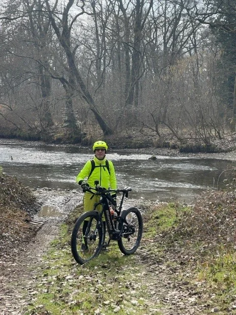 川沿いで自転車を持った黄色いジャケットを着た男性