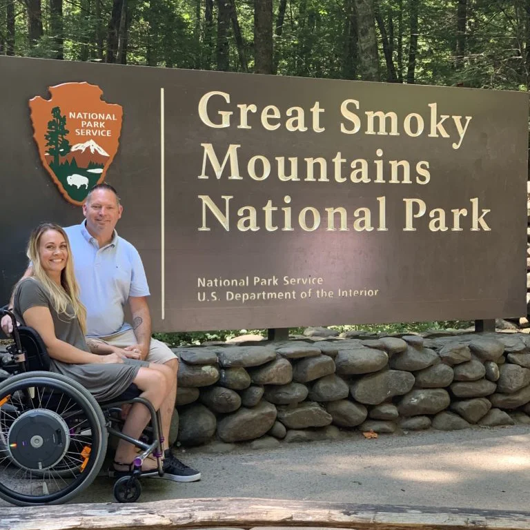 a man and a woman in a wheelchair by a sign