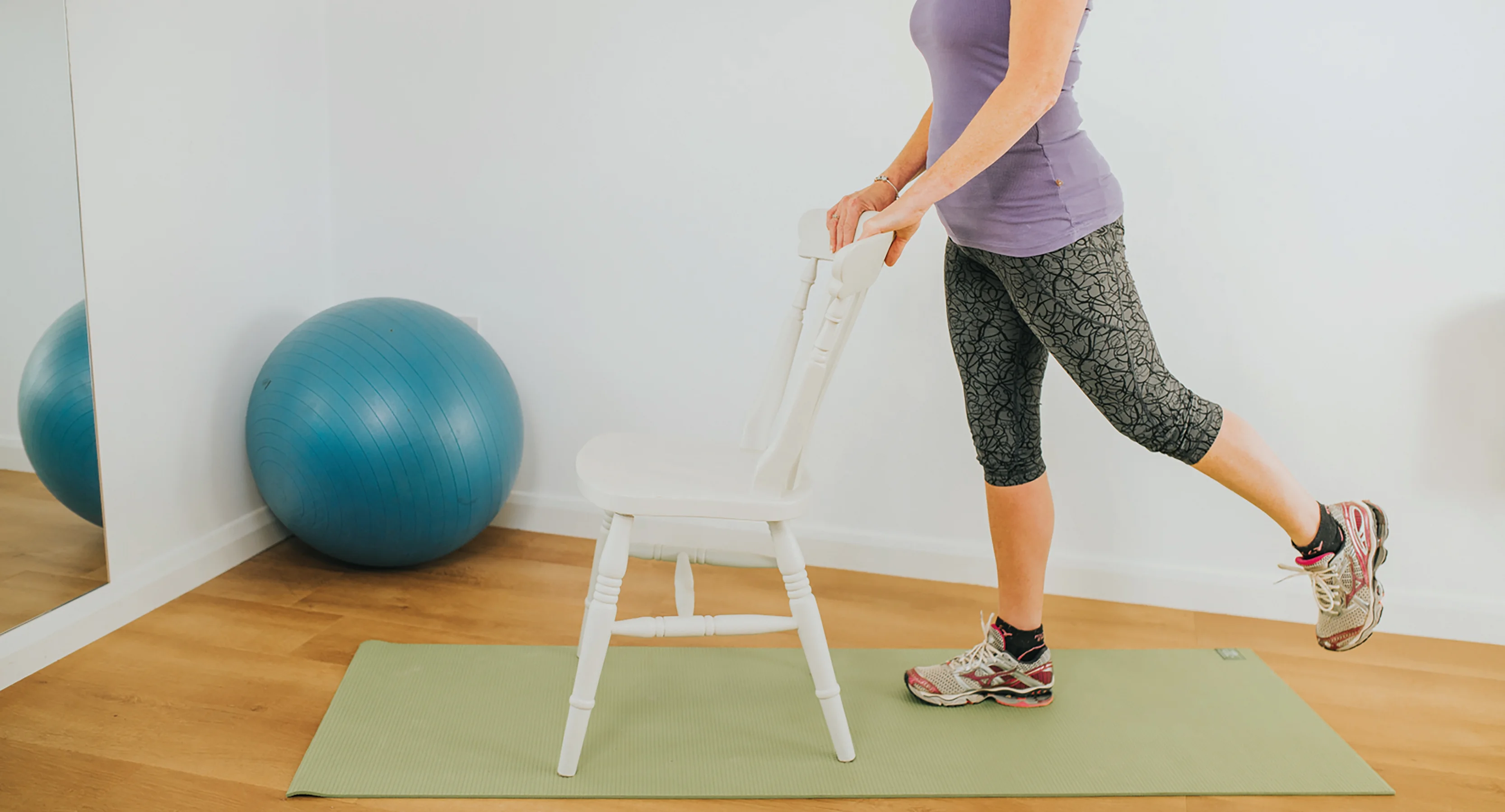 une personne debout sur un tabouret avec une boule bleue devant le